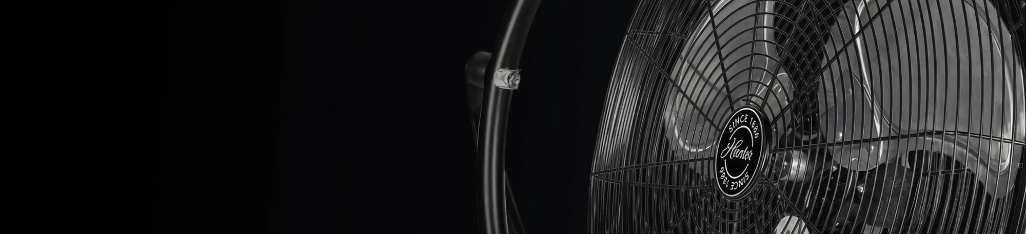 Close-up of a wall mount fan on a black background.