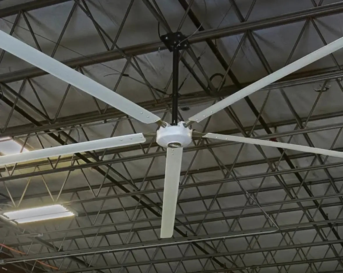 Hunter Industrial Titan HVLS fan in high-bay warehouse with dark steel truss ceiling